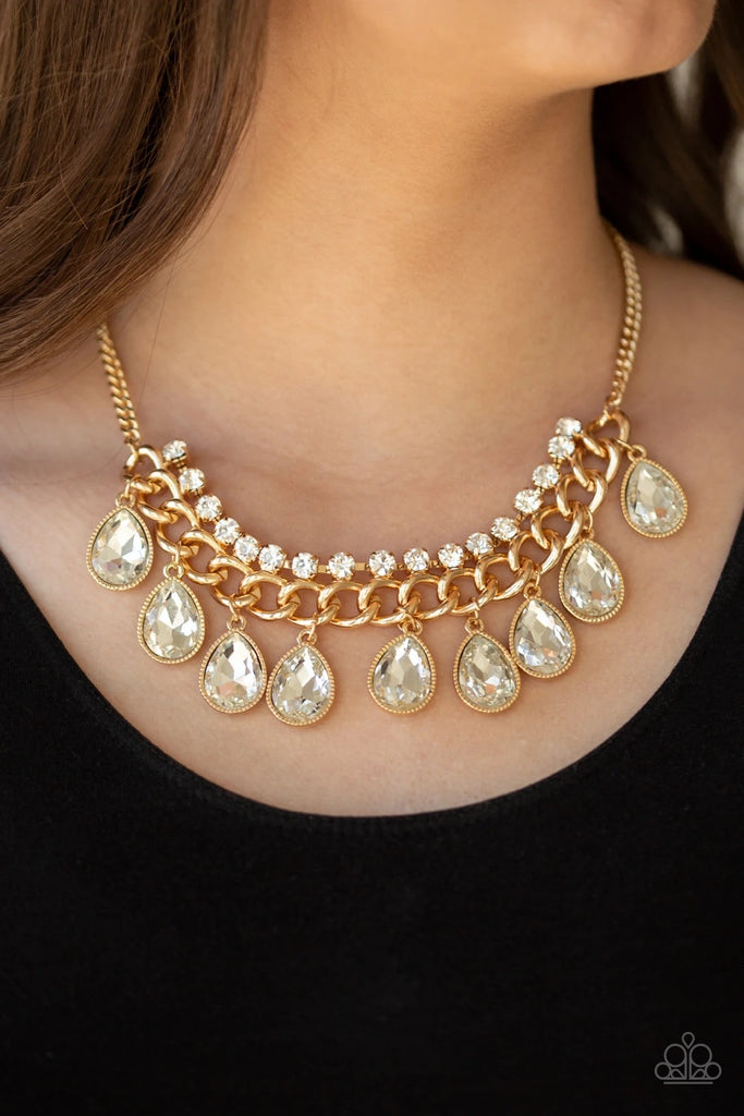 Teardrop rhinestones swing from the bottom of a bold gold chain, creating a dramatic fringe below the collar. A strand of glittery white rhinestones attach to the top of a shimmery gold chain, adding a refined flair to the flashy statement piece. Features an adjustable clasp closure.  Sold as one individual necklace. Includes one pair of matching earrings.