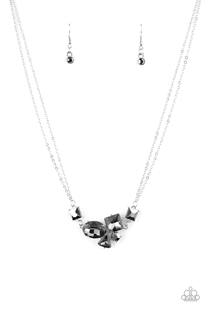 Varying in shape and size, triangular, round, and square cut hematite and smoky rhinestones coalesce into a floating pendant at the bottom of doubled silver chains, creating a stellar shimmer below the collar. Features an adjustable clasp closure.  Sold as one individual necklace. Includes one pair of matching earrings.