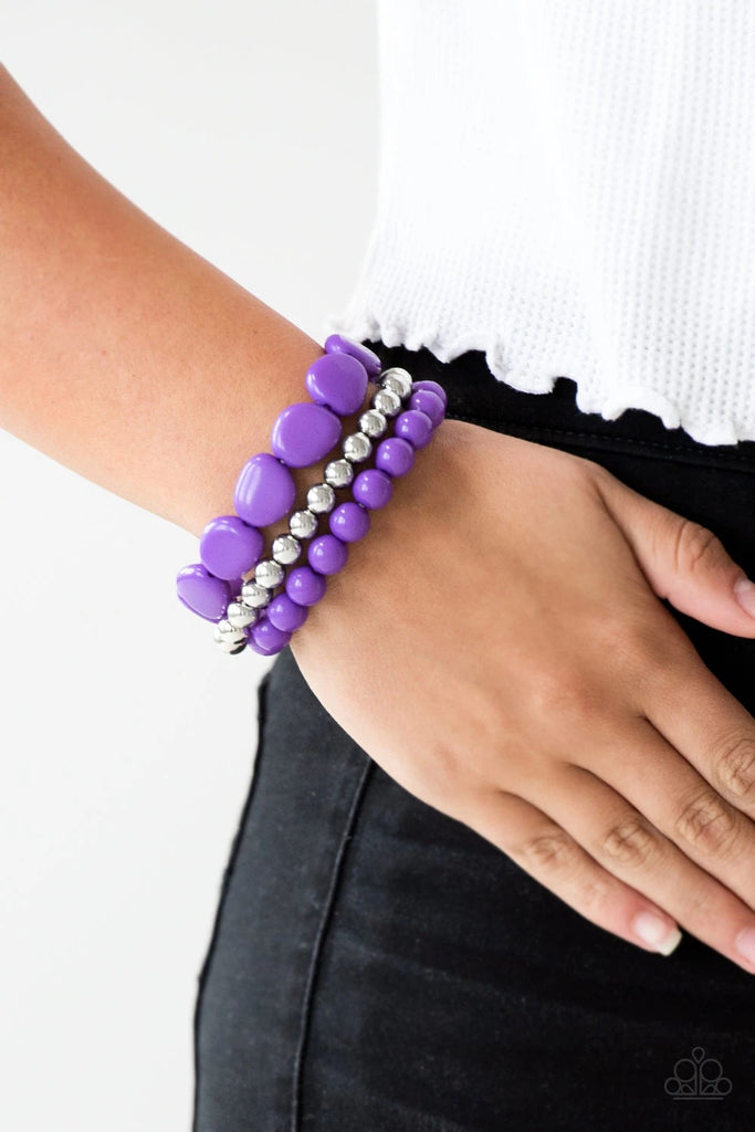 Varying in size, vivacious purple and glistening silver beads are threaded along stretchy bands, creating colorful layers across the wrist.  Sold as one set of three bracelets.  