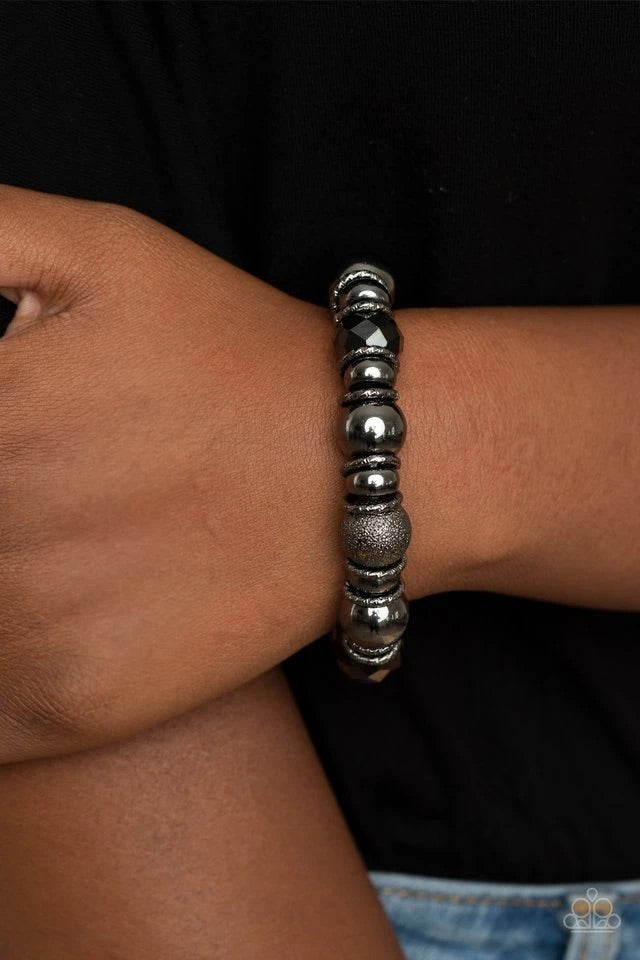 A glittery compilation of mismatched gunmetal beads, gunmetal rings, and sparkly hematite crystal-like beads are threaded along a stretchy band around the wrist for an edgy glow.  Sold as one individual bracelet.  