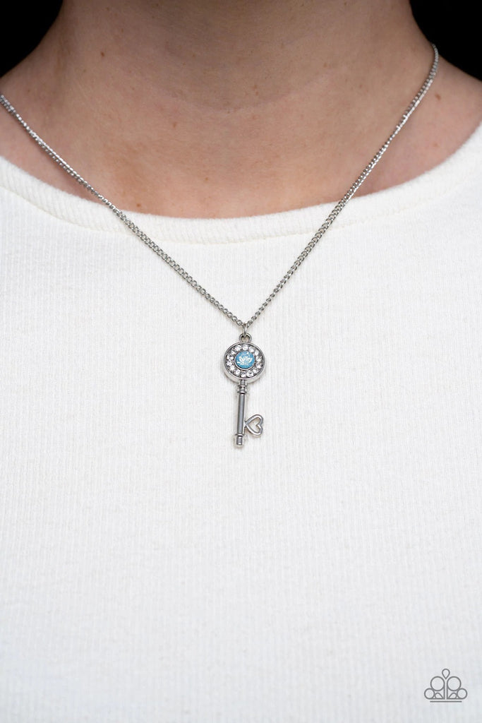 Bordered in glassy white rhinestones, an opal blue rhinestone adorns a shiny silver key pendant at the bottom of a dainty silver chain for a whimsical fashion. Features an adjustable clasp closure.  Sold as one individual necklace. Includes one pair of matching earrings.